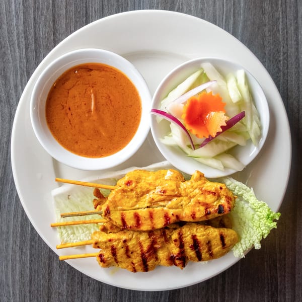 Grilled chicken satay skewers with peanut sauce and a side of cucumber salad.