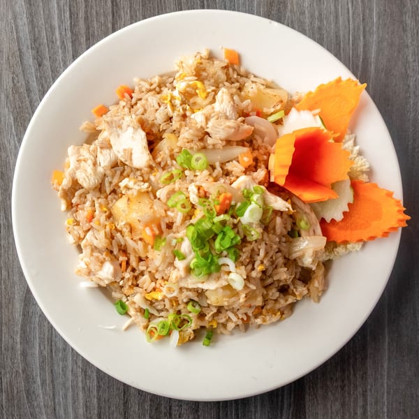 Chicken fried rice with pineapple, carrots, and scallions, garnished with carved carrots.