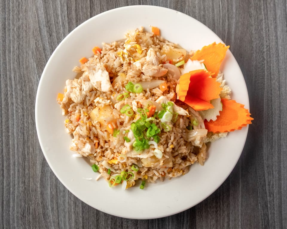 Chicken fried rice with pineapple, carrots, and scallions, garnished with carved carrots.